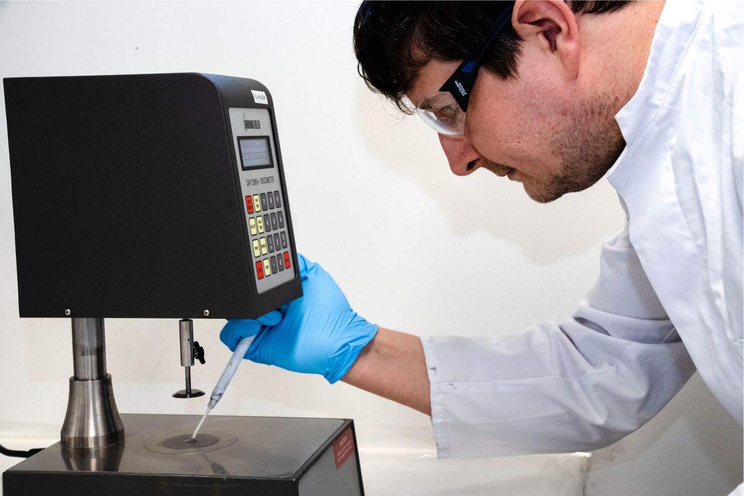 Un uomo con un camice bianco versa qualcosa da una pipetta su una superficie